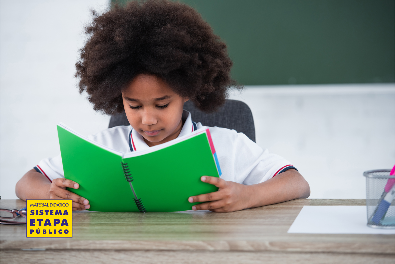 Menina lendo livro na educação infantil em sala de aula, representando o desenvolvimento da leitura e contação de histórias alinhada à BNCC
