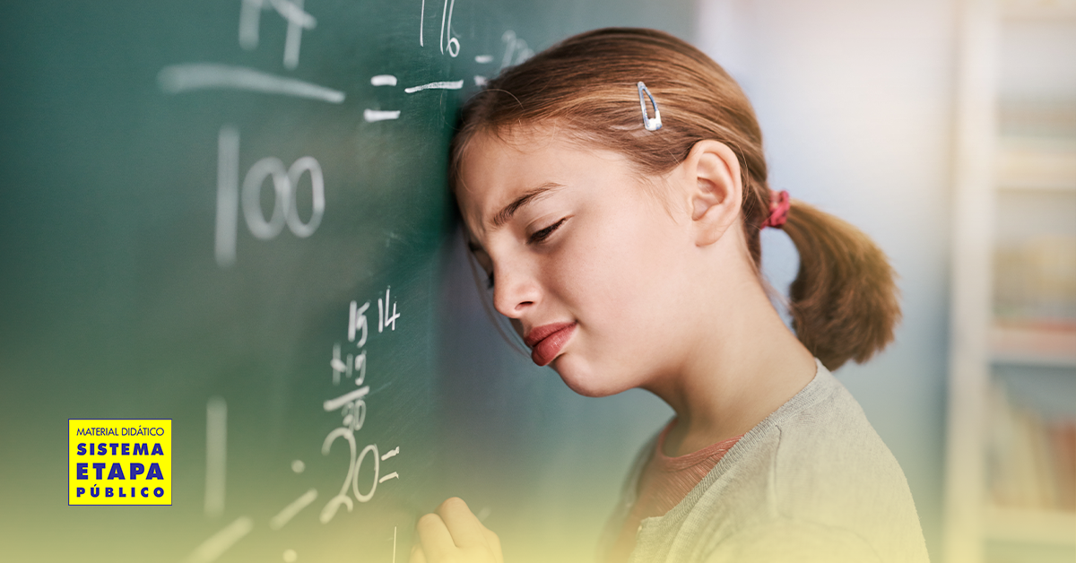 Garotinha com expressão de esforço tentando entender conceitos de matemática na lousa, ilustrando dificuldades relacionadas à discalculia.