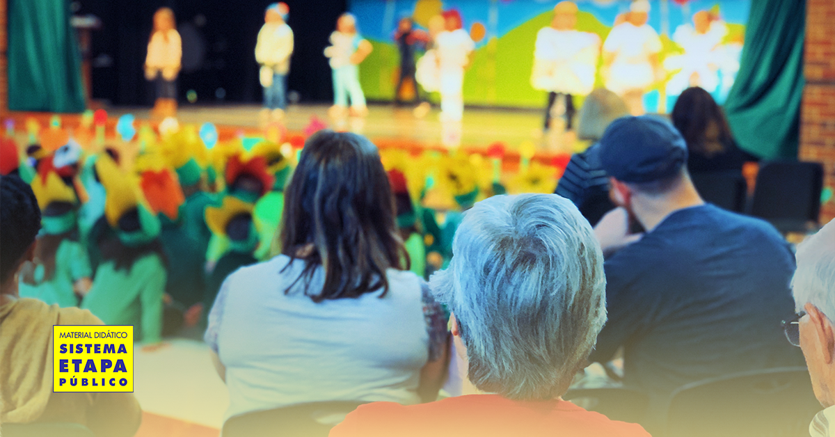 Apresentação teatral com crianças do ensino fundamental anos iniciais, palco com atores e público infantil assistindo a peça de teatro educativa.