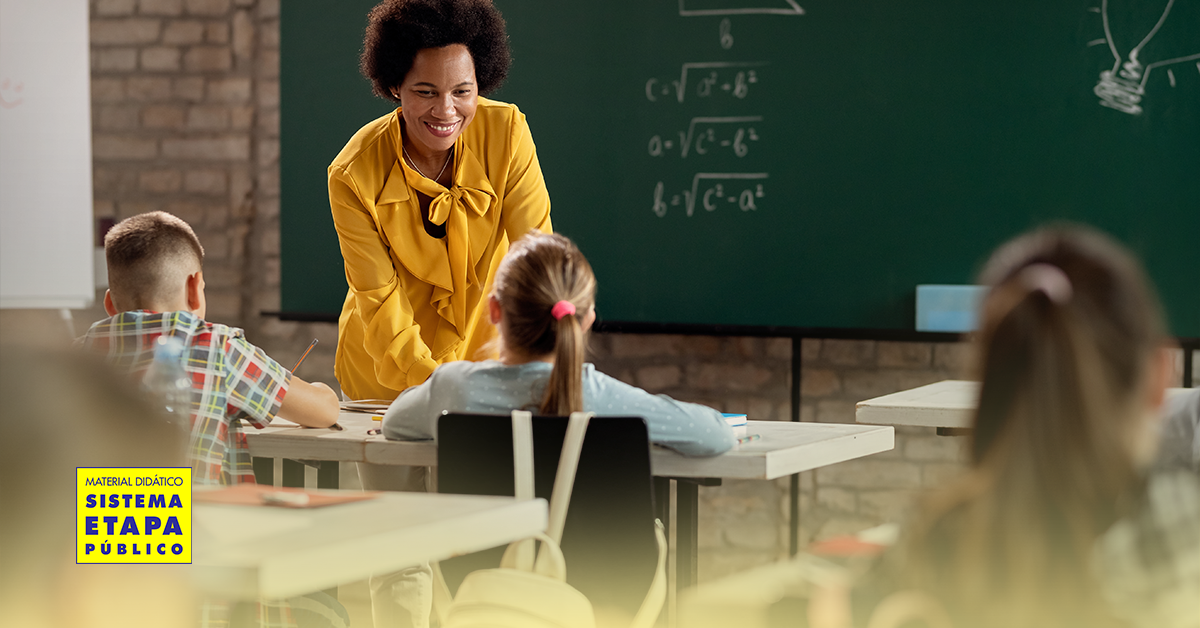 Professora da escola pública orienta alunos em sala de aula, promovendo aprendizagem, diálogo e desenvolvimento integral dos estudantes.