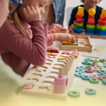 Crianças da Educação Infantil participam de atividades lúdicas com jogos de encaixe, blocos coloridos e materiais pedagógicos, em um ambiente escolar acolhedor e colaborativo.
