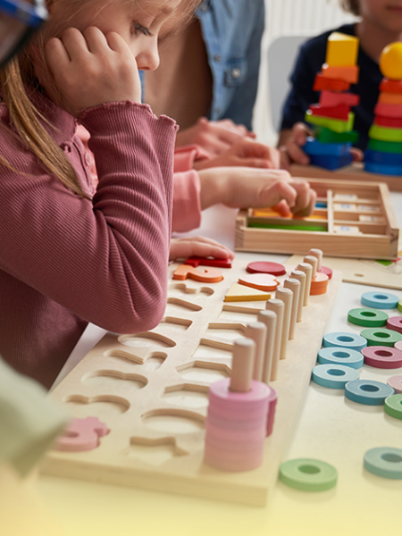 Crianças da Educação Infantil participam de atividades lúdicas com jogos de encaixe, blocos coloridos e materiais pedagógicos, em um ambiente escolar acolhedor e colaborativo.