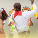 Pessoas com fantasias coloridas e máscaras celebrando o Carnaval, representando as raízes históricas e culturais da festa no Brasil.