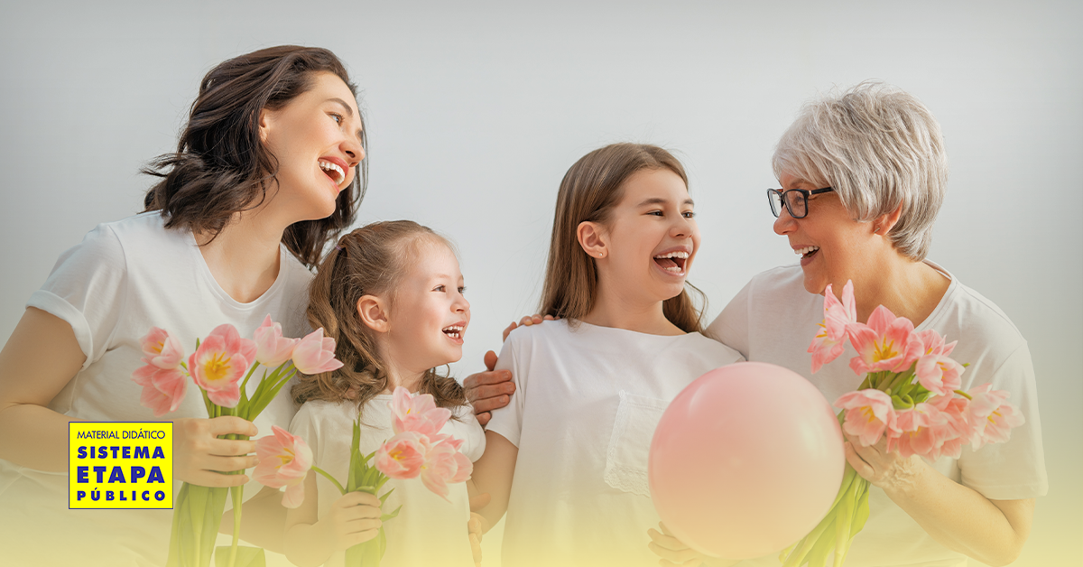 Três gerações de mulheres — avó, mãe e filhas — sorrindo e segurando flores em celebração ao Dia Internacional da Mulher, representando união, respeito e valorização feminina na educação.