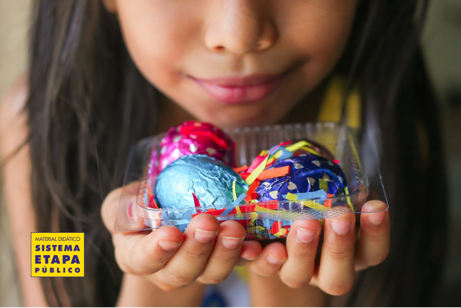 Criança segurando ovos de Páscoa coloridos em embalagem, representando atividades escolares relacionadas à Páscoa e ao aprendizado lúdico.