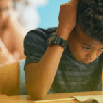 Aluno frustrado em sala de aula durante atividade escolar, ilustrando desafios de aprendizagem e desenvolvimento socioemocional.