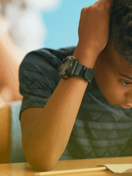 Aluno frustrado em sala de aula durante atividade escolar, ilustrando desafios de aprendizagem e desenvolvimento socioemocional.